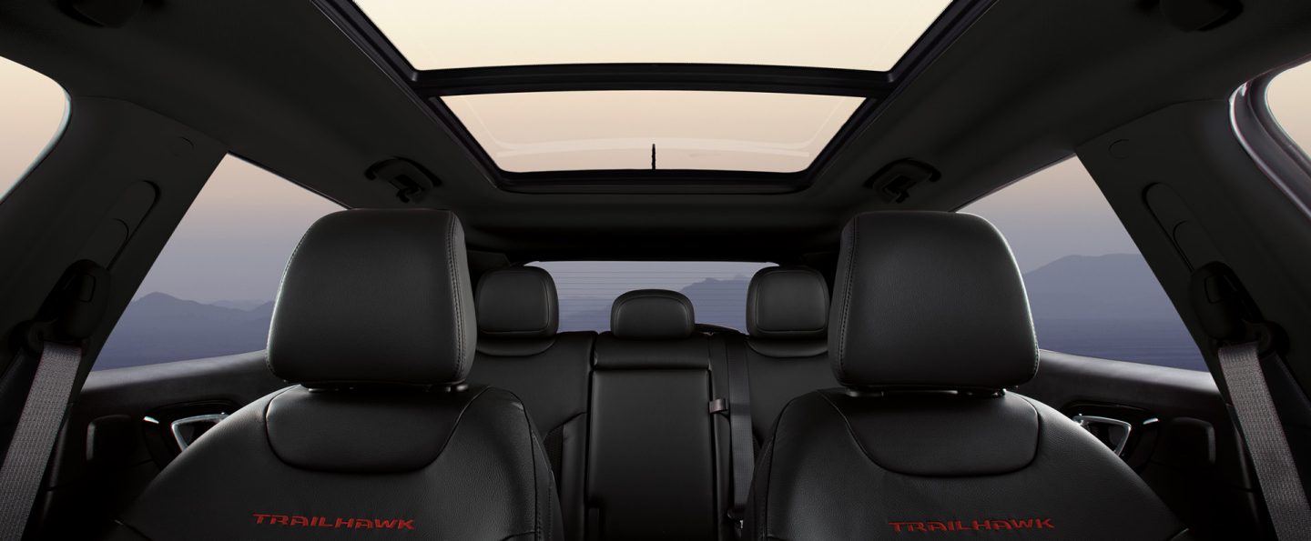 The interior of the 2025 Jeep Compass Trailhawk focusing on the front and rear seats and the panoramic sunroof.