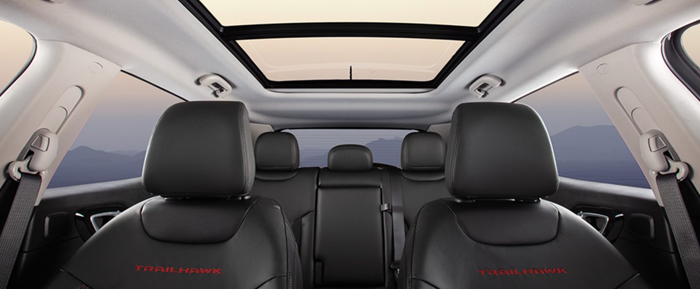 The interior of the 2025 Jeep Compass Trailhawk focusing on the front and rear seats and the panoramic sunroof.