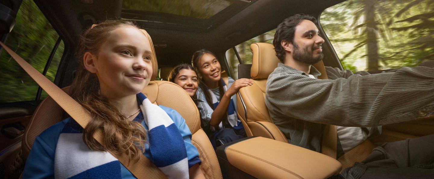 The interior of the 2025 Jeep Grand Cherokee Summit with the driver and three passengers inside--one in the front passenger seat and two in the second row.