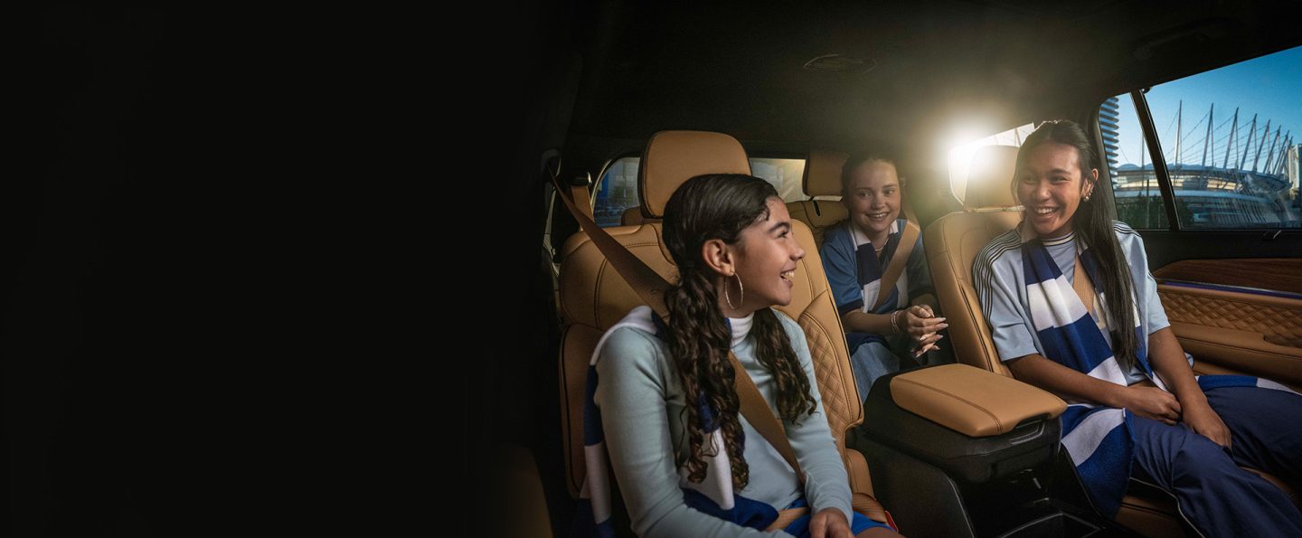 The interior of the 2025 Jeep Grand Cherokee L Summit Reserve with two children seated in the second row and one child seated in the third row.