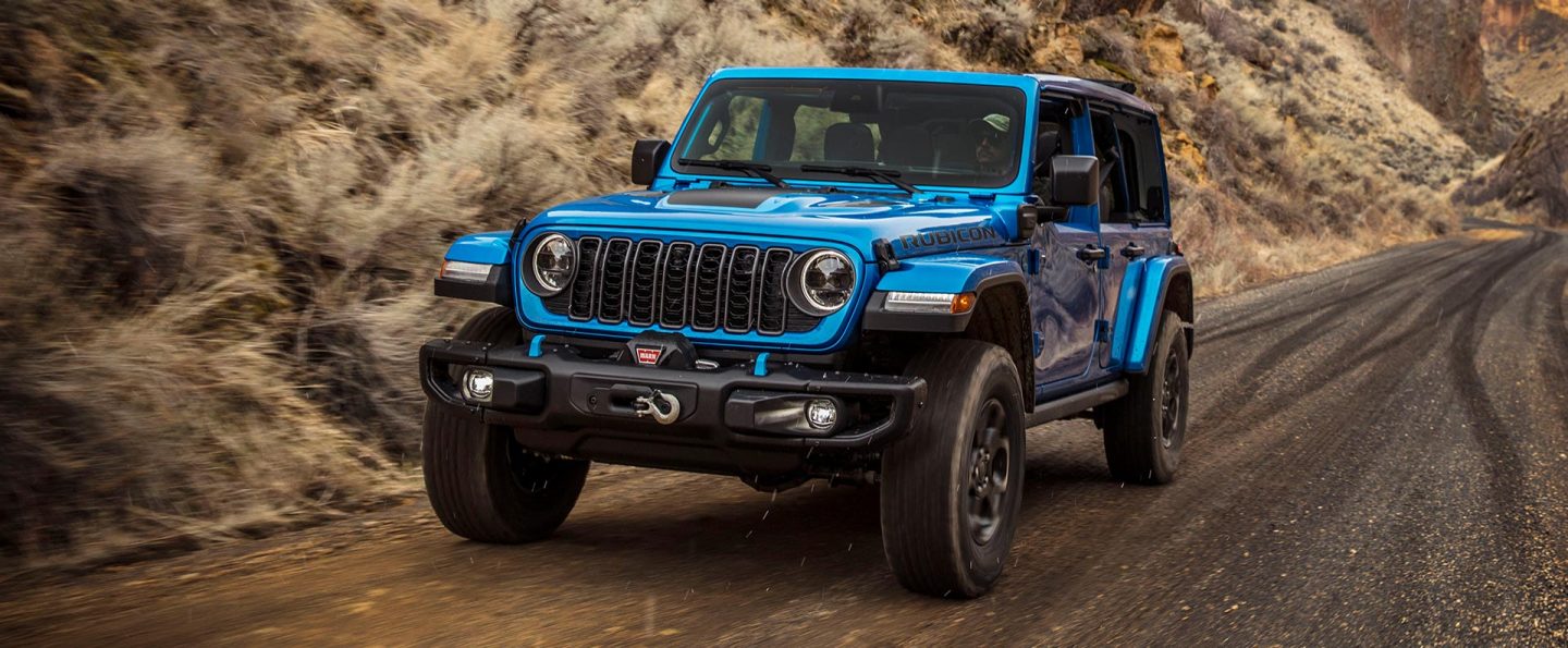 A blue 2025 Jeep Wrangler X 4xe traveling on a highway.