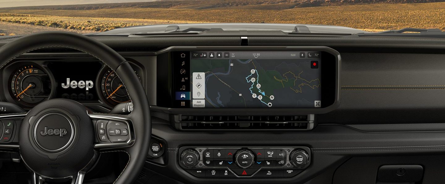 The steering wheel, Digital Cluster Display and Uconnect touchscreen in the 2025 Jeep Wrangler with the touchscreen displaying one of the Off-Road Trail Guides.