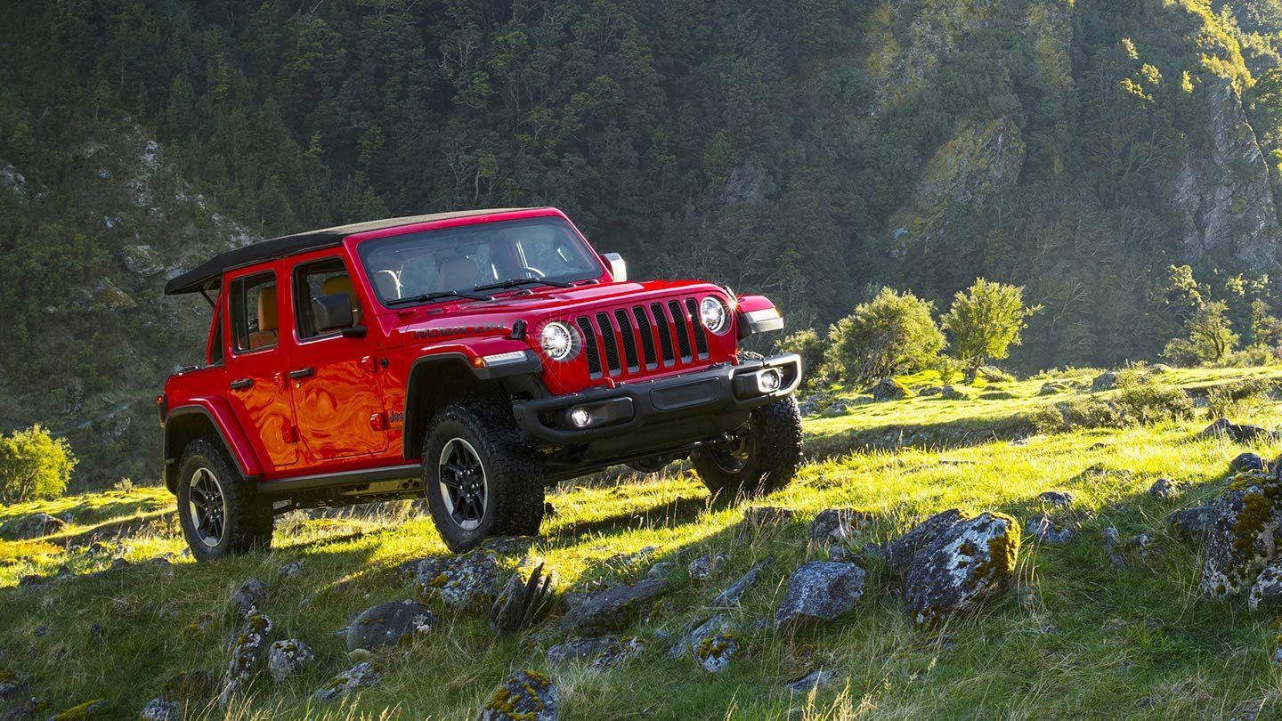 A red jeep parked in front of a louis vuitton store photo – Free